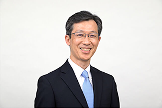 スーツ姿で微笑む南日豊の写真